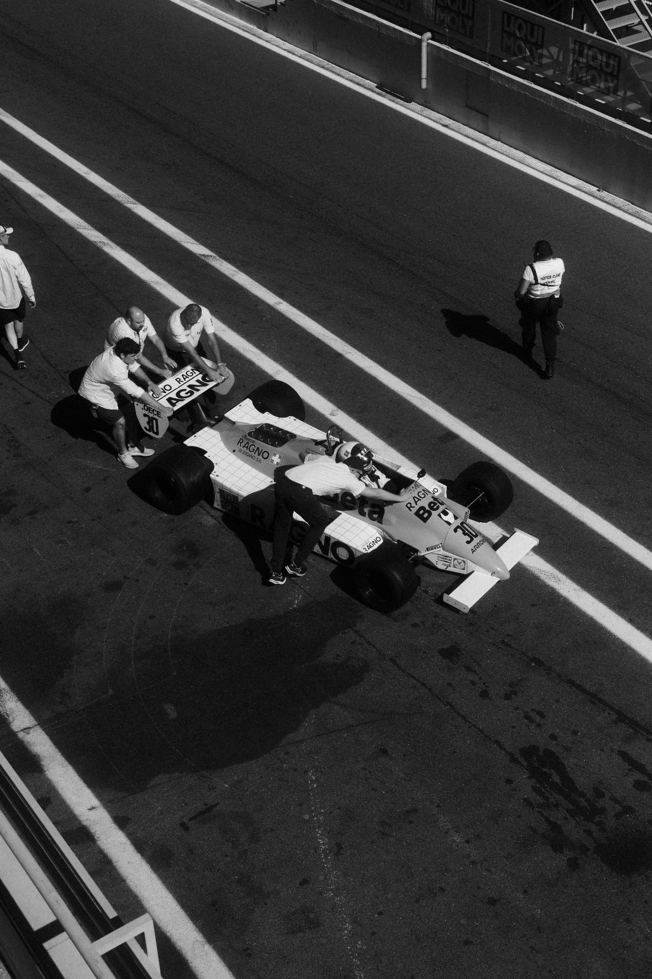 A V10-era Formula 1 car in the pit lane at Estoril Classics, black and white