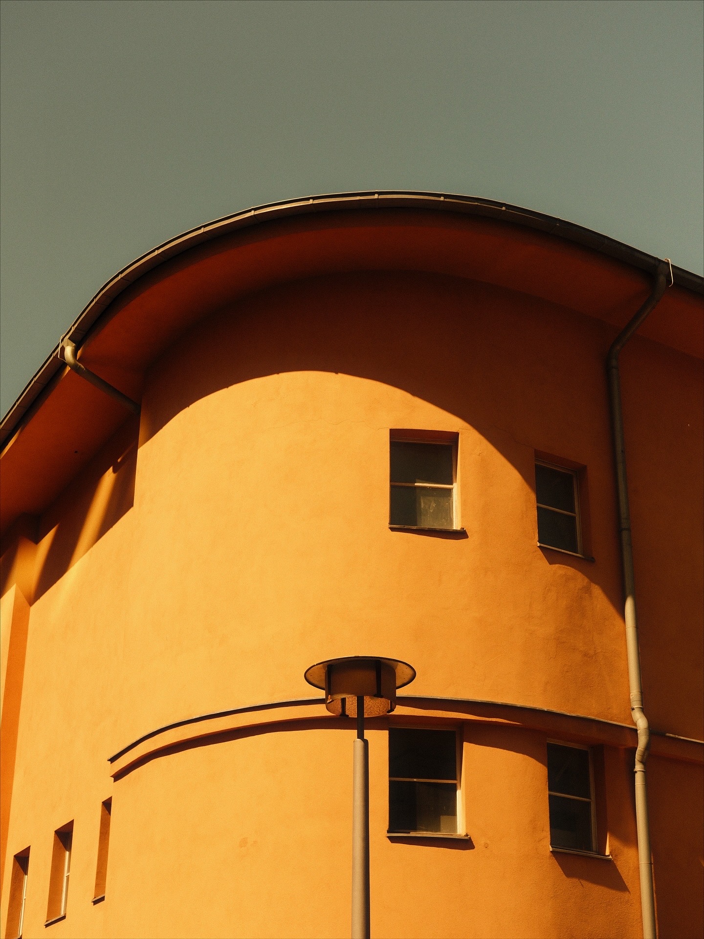 Curved ochre wall under a flat grey sky