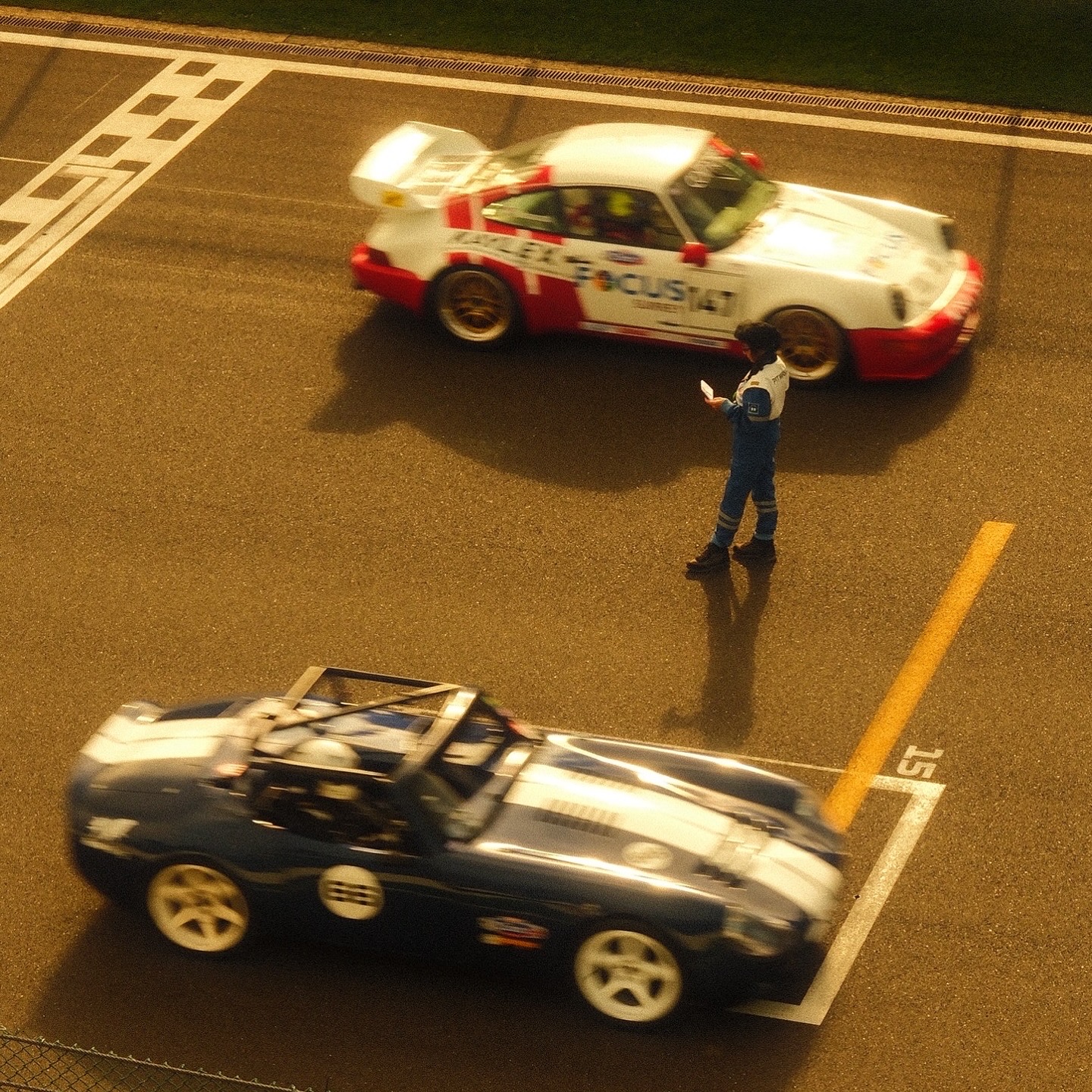 A marshal alone on a pit straight with cars blurring past