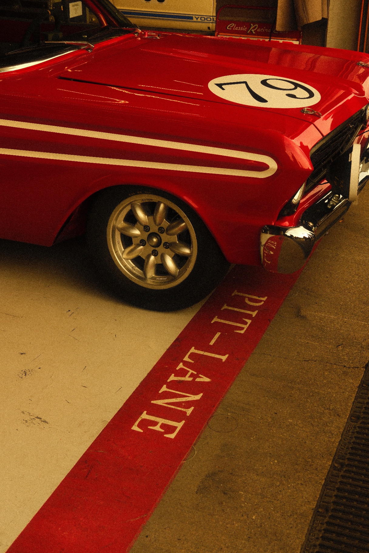 Red vintage race car over pit-lane stripe