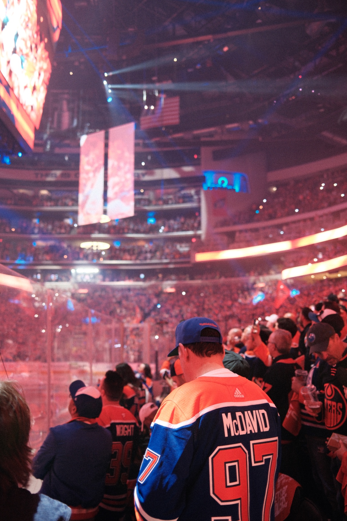 Oilers crowd from rink-side with McDavid jersey in foreground