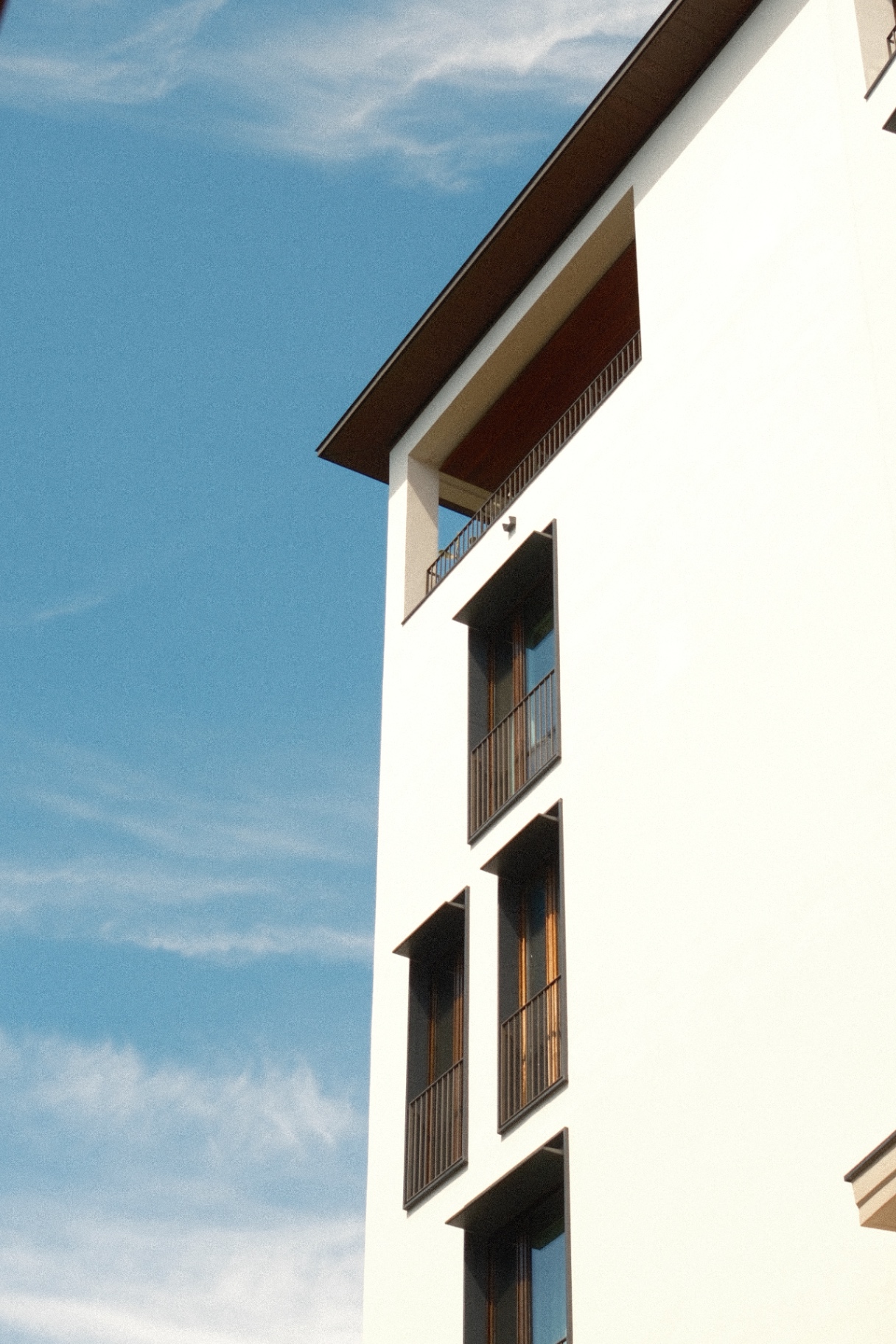 White stucco facade with shuttered balconies against a soft blue sky