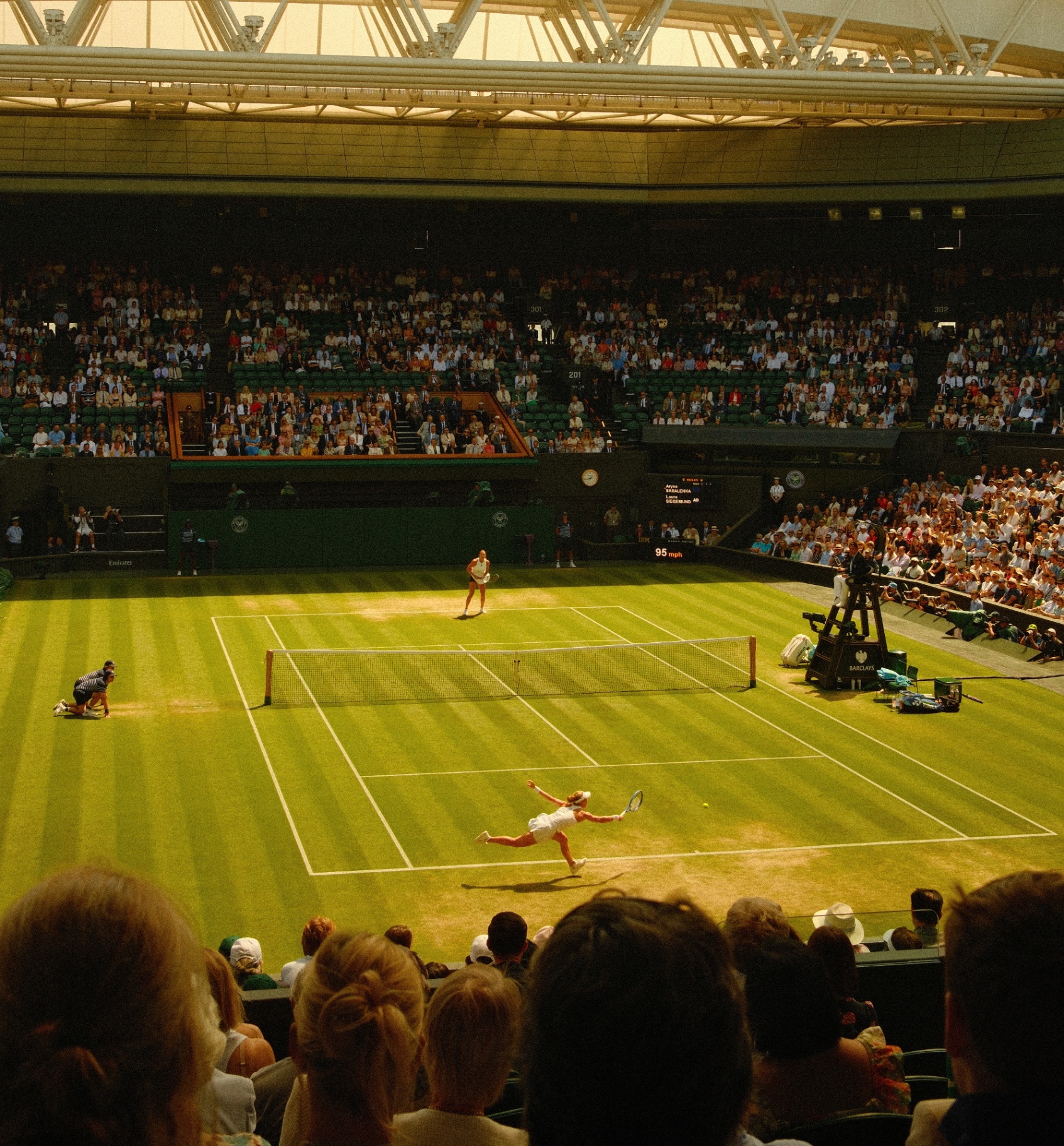 Wide view of Centre Court at Wimbledon, player stretching for a return