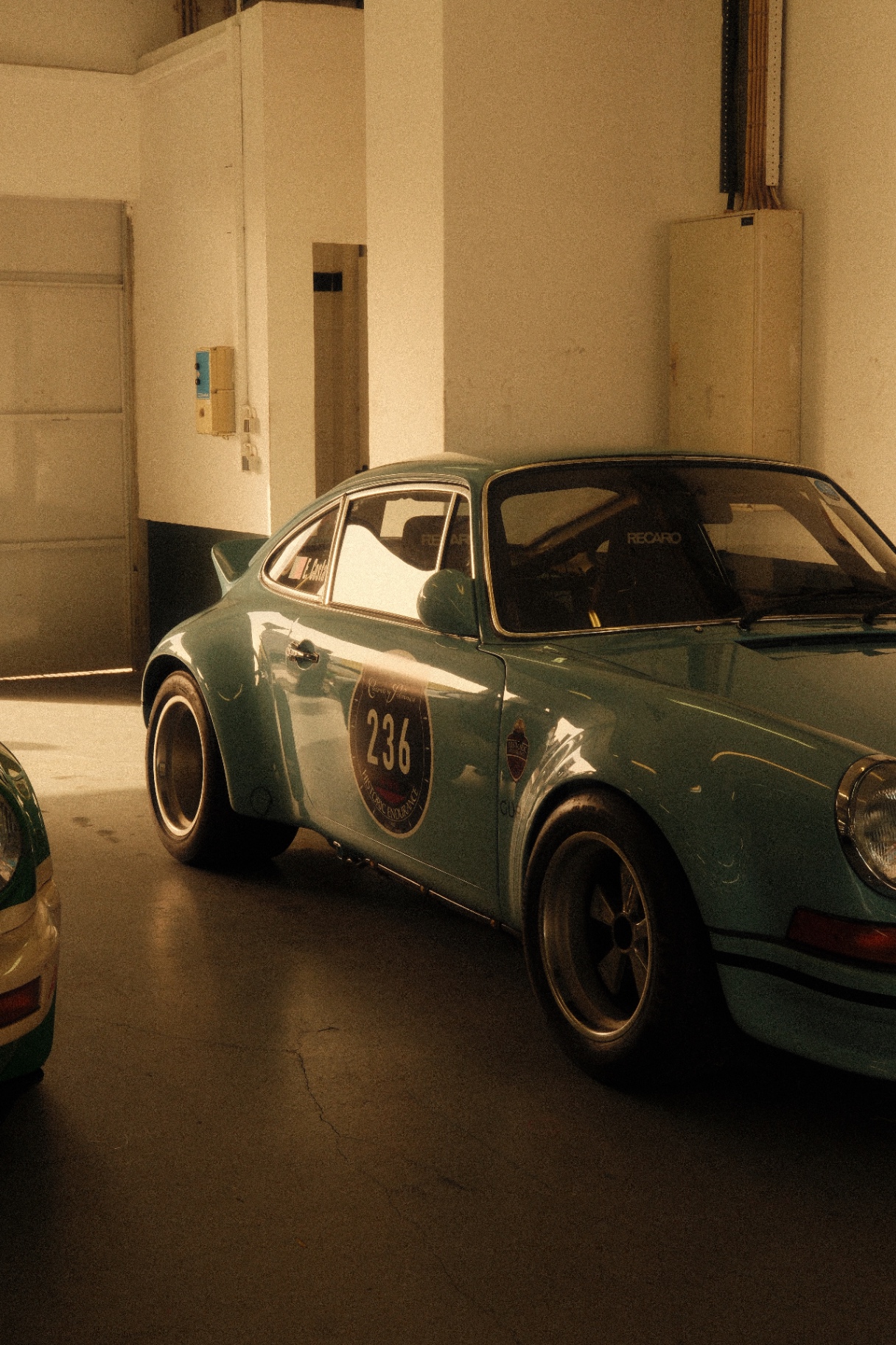 Mint-green 911 race car in the paddock