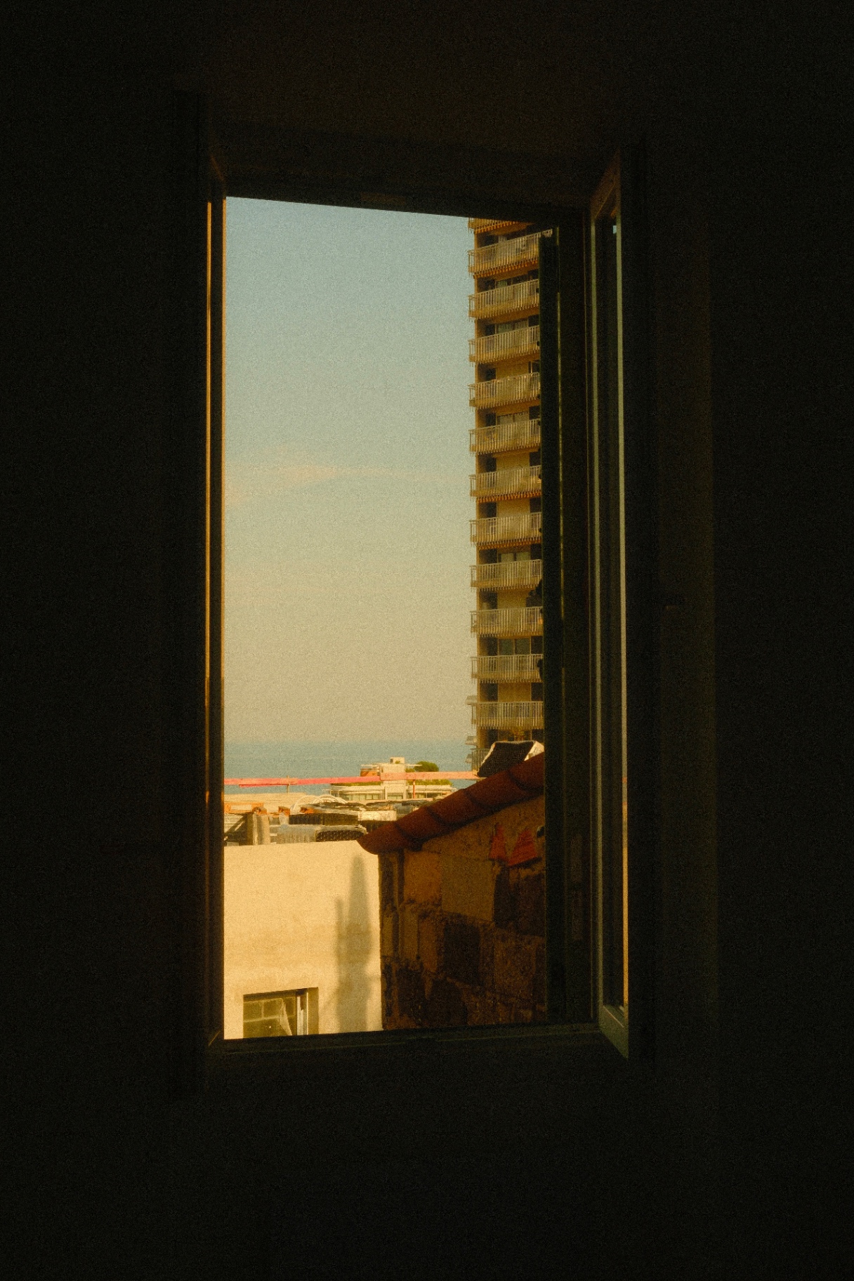Open window framing the sea and a tall balcony tower