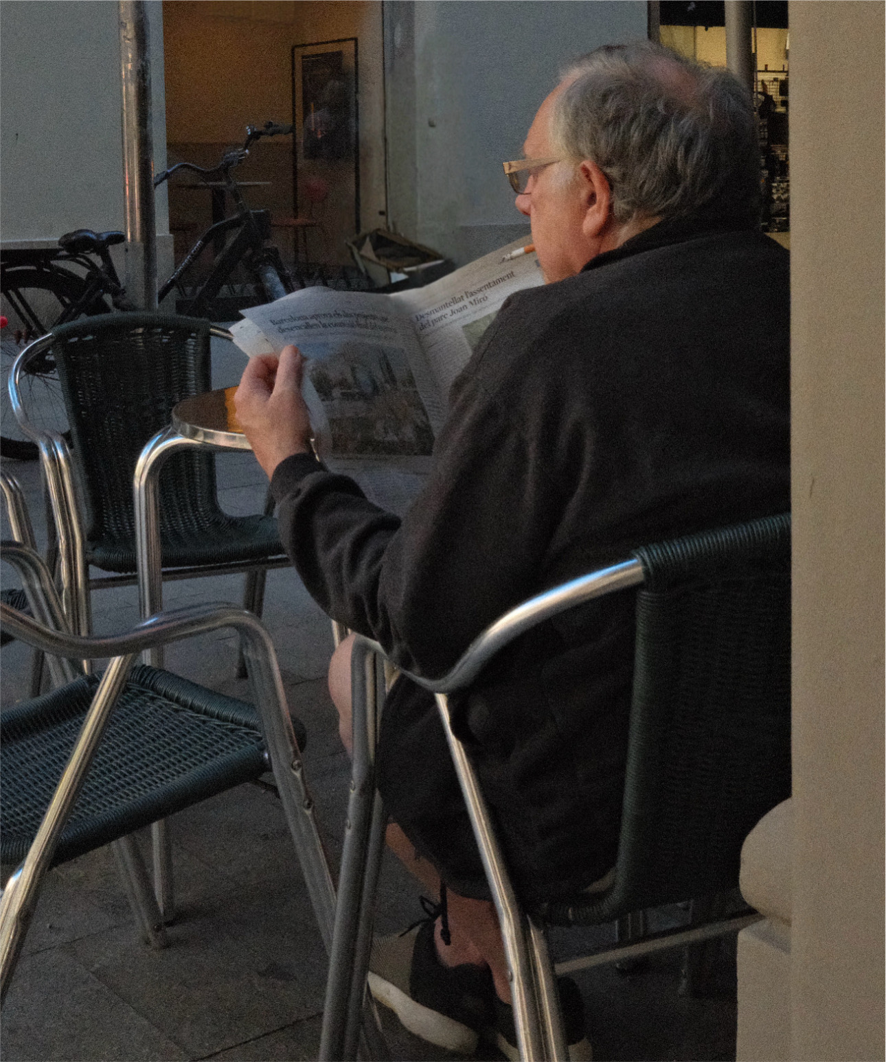 Man reading a newspaper at a café terrace in Barcelona