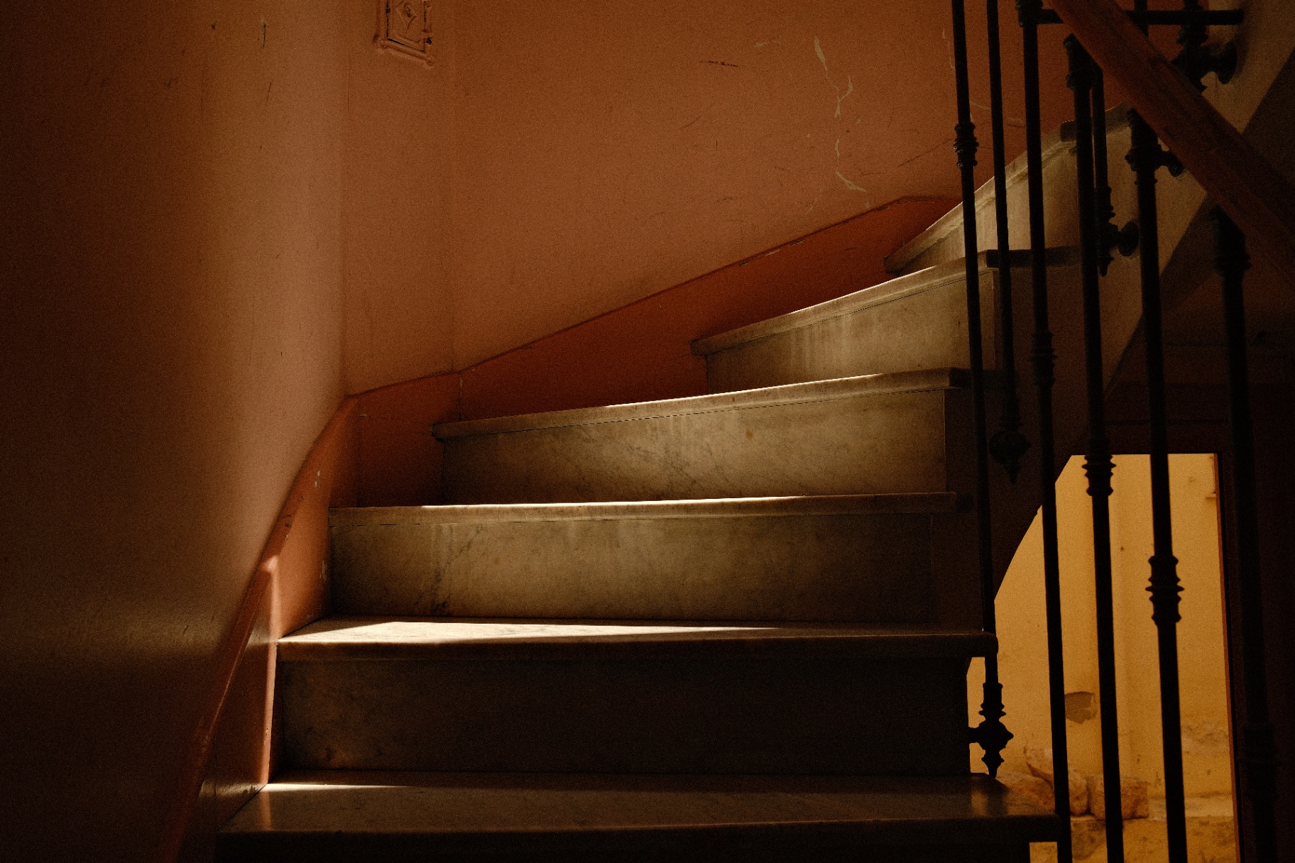 Marble staircase in warm light with wrought-iron banister
